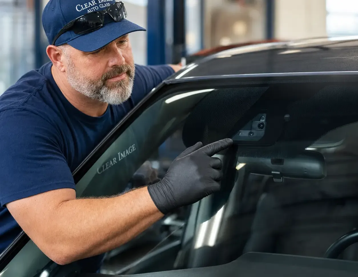 Technician inspecting windshield ADAS equipment and vehicle features