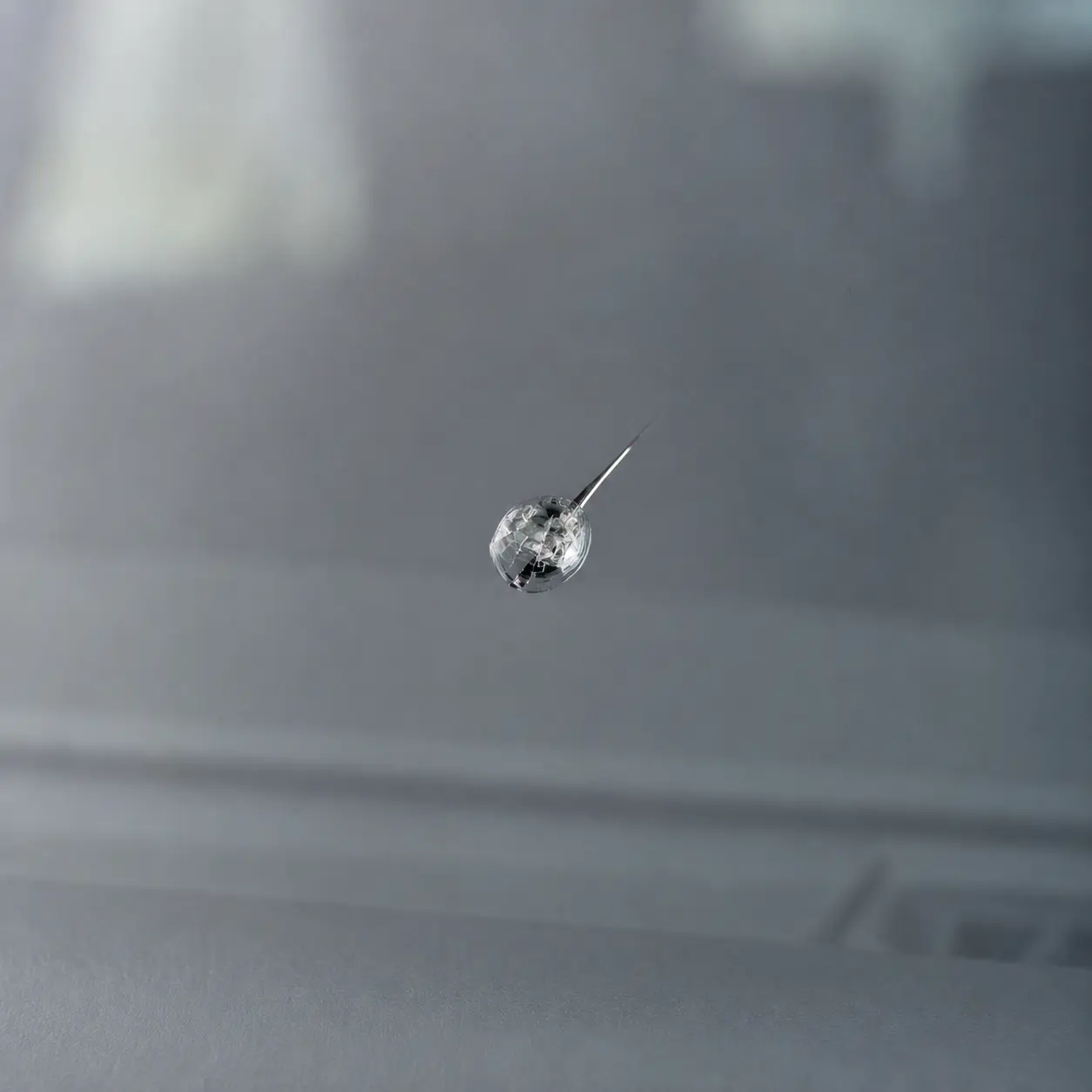 Close-up of a windshield chip with a short crack beginning to spread
