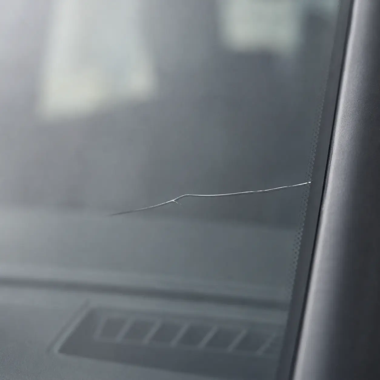 Close-up of a long windshield crack extending from the edge of the glass