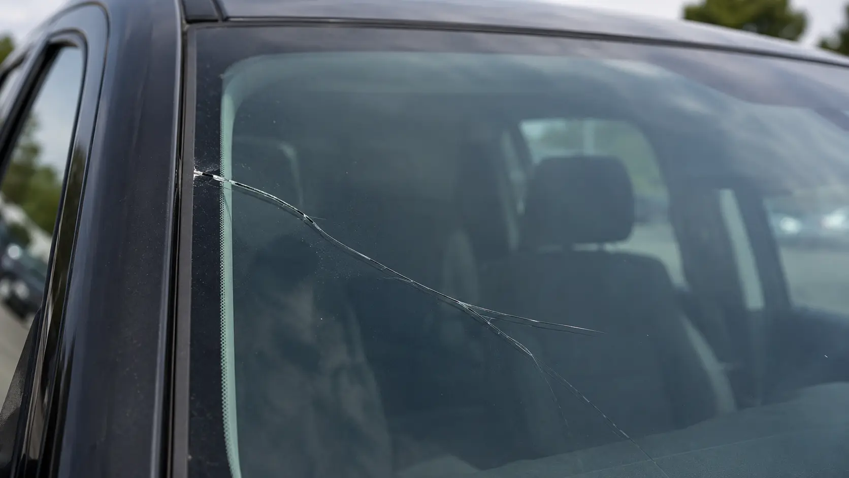 Close-up of a long windshield crack extending near the edge of the glass