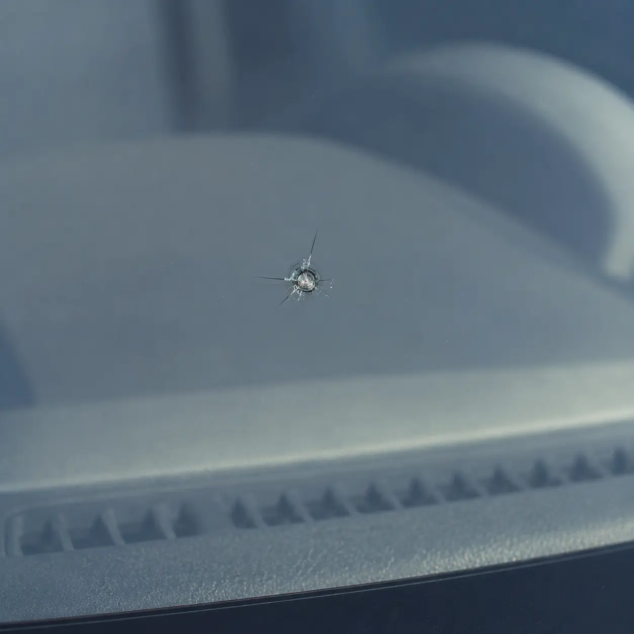 Close-up of rock chip damage in a windshield before professional repair